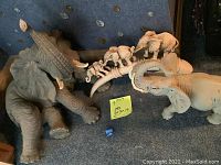Photo showing all three ceramic elephant figurines together: one large seated elephant, one standing elephant with raised trunk, and a curved base with three small elephant figurines.