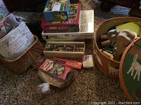 Overview of puzzles, games, marbles, and wooden toy container with ping pong paddles on carpet