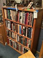 Front view of the oak 4-shelf bookcase filled with books to show scale and condition.