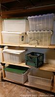 Photo of shelving unit with several plastic storage bins stacked, various sizes and colors, some lids missing or on side