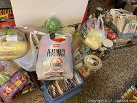 Photo showing multiple plastic bags filled with yarn balls, spools of thread, buttons, and other sewing notions scattered on carpeted floor and some organized in crates.
