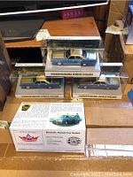 Three gold-roof/dark-blue-body Pennsylvania State Police model cars in clear plastic display cases on a desk.