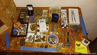 Overview of collection on table including boxes, pins, rings, pens, patch, and medallions.