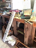 Photo showing wooden toolbox, metal boxes, boxed shoplight, and other miscellaneous items on workbench.