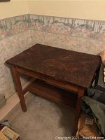 Wood writing table with marbled top surface, single drawer with wooden knob and lower shelf, showing wear and scratches.