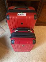 Front view of both red Heys luggage pieces stacked, showing textured red hard-shell, black handles, and corner protectors.