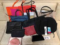 Full view of the twelve assorted handbags, purses, totes, and clutches in various colors and materials arranged on a beige surface.