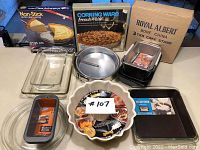 Overview of baking pans, glass dishes, and boxed items including bundt pan, glass dishes, loaf pans, springform pan, and boxed Royal Albert cake stand plates.