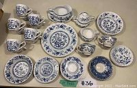 Overview of 39 blue and white fine china pieces arranged, including cups, plates, gravy dish, cream and sugar bowls.