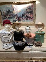 Hats of various styles on mannequin heads arranged with several hat boxes.