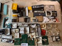 Overhead photo showing many small jewelry boxes and pouches with pieces inside, including bracelets, earrings, necklaces