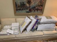 Full view of pillows and bedding items stacked on a couch, showing the variety of packaged items.