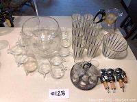 All items arranged on tabletop showing punch bowl set, shot glasses on tray, bottle stoppers, striped glassware, matching bowl and Pyrex jug
