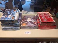 Seven branded boxes of Cristal d'Arques glassware on table – blue boxes for rocks glasses, red boxes for Cheverny highball tumblers