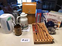 Full view of the items in the lot including electric kettles, thermos set, yogurt maker box, breadboard and kitchen utensils.
