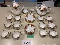 Overall view of two pots, cups and saucers arranged on table with green label '28 PIECES'