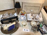 Full view of lot showing boxed salt and pepper shakers, floral plates, silver trays, silver cutlery, and sake set cups