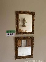 Two vintage mirrors mounted vertically on wall, showing detailed carved wooden frames with floral patterns and gold finish.