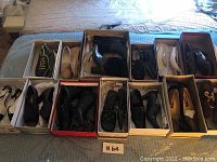 12 pairs of women's shoes in boxes arranged on a bed, showing mix of styles and colors.