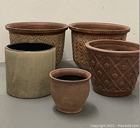 Five pots arranged: two large patterned terra cotta at back, right medium patterned pot, left medium grey pot, small terra cotta in front