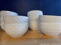 Photo showing six white stoneware bowls with various mid-century modern geometric embossed patterns lined up.