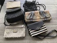 All seven assorted evening and makeup bags displayed on wooden floor