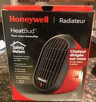 Photo of Honeywell HeatBud heater box showing product image and features in French and English, demonstrating compact size and safety features with two heat settings.