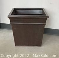 Side front view of large square metal plant holder showing dark bronze color and tapered body