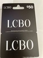 Photo showing two black LCBO gift cards placed on a white surface, each valued at $50 and unactivated.