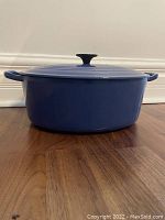 Side profile view of the blue oval Dutch oven with lid on, showing two side handles and smooth enameled finish.
