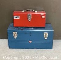 Photo of two metal tool boxes: smaller red box on top of larger blue box against neutral background.