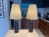 Two grey ceramic table lamps with cream textured shades displayed on counter in kitchen setting