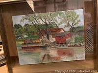 Framed watercolour painting showing the steel-hulled oil transport boat by the water with trees and small structures nearby. Signed 'R Smith'.