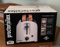 Box of Proctor Silex 2-slice toaster showing image of white and silver toaster with bread slices inside.