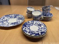 Photo showing the assorted pieces including cups, saucers, plates arranged on a table.