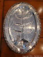 Oval silver plate roast platter with grooved center to hold juices and ornate silver plate feet raising the platter 1.5 inches above surface.