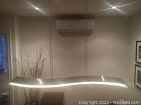 Installed view of wave-shaped chandelier suspended over table