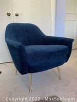 Front view of blue upholstered armchair with gold-tone metal tapered legs