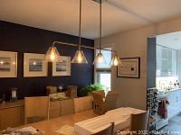Fixture installed over dining table, showing four lighted glass cones and overall condition