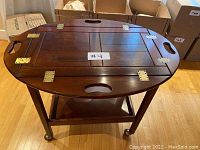 Top front view of the Bombay Company dinner serving cart showing foldable hinged wooden sides and cut-out handles.