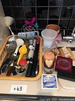 Photo of kitchen utensils including graters, slicers, peelers, measuring cups, brown sugar keeper, garlic keeper and crystal coasters in a woven basket