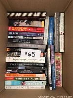 Box of 25 novels showing titles on the spines including The Girl Who Takes Heart for a Bite, Disgrace, White Oleander, Still Alice, The Reader, among others.