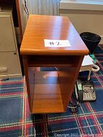 Side table top surface and side profile showing medium brown wood grain and caster wheels underneath.