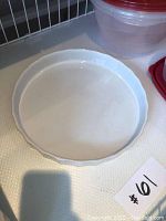 White ceramic pie dish with fluted edges shown on white surface with lot tag number 61.
