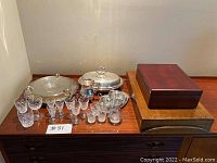 Overview of entire lot including silver plated serving dishes, crystal glasses, wooden cigar humidor and cutlery boxes