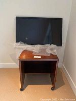 Magnavox flat-screen TV on top of a wooden rolling table with casters, bubble wrap covering the table surface.