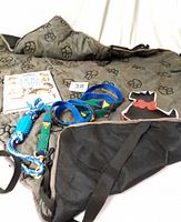 Overall lot showing the dog car seat protector, leash, dish, rope toy, and book