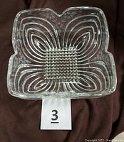 Top view of the clear crystal square bowl showing floral embossed design and textured center grid.