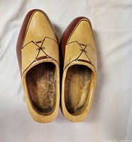 Pair of natural and ox wood wooden clogs shown from top view, displaying hand-painted finish and metal nail details.