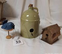 Image showing the three items together: ceramic jug-style birdhouse, wooden birdhouse, and blue bird figurine